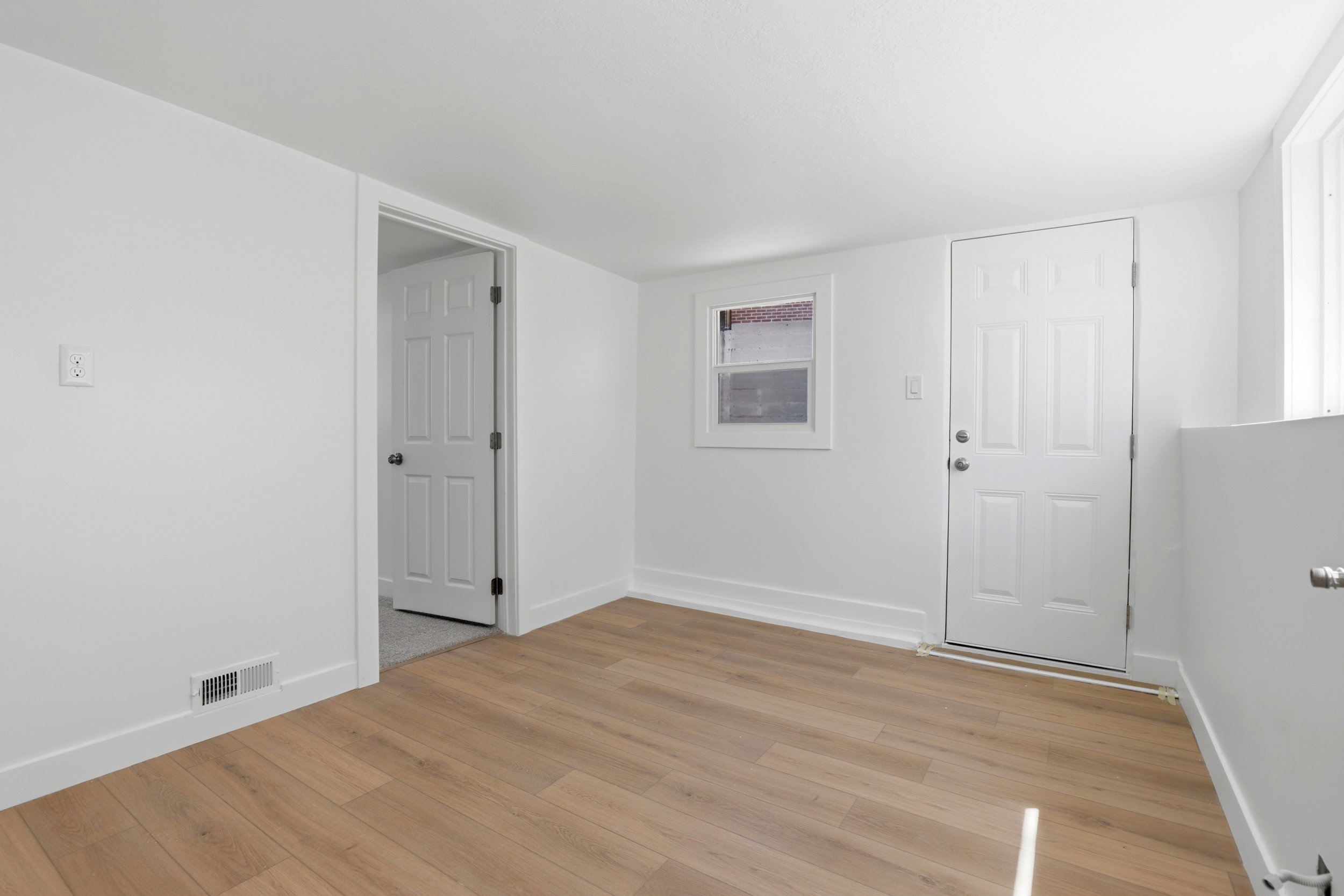 Bright interior space featuring light wood-finish flooring, white walls, and white trim