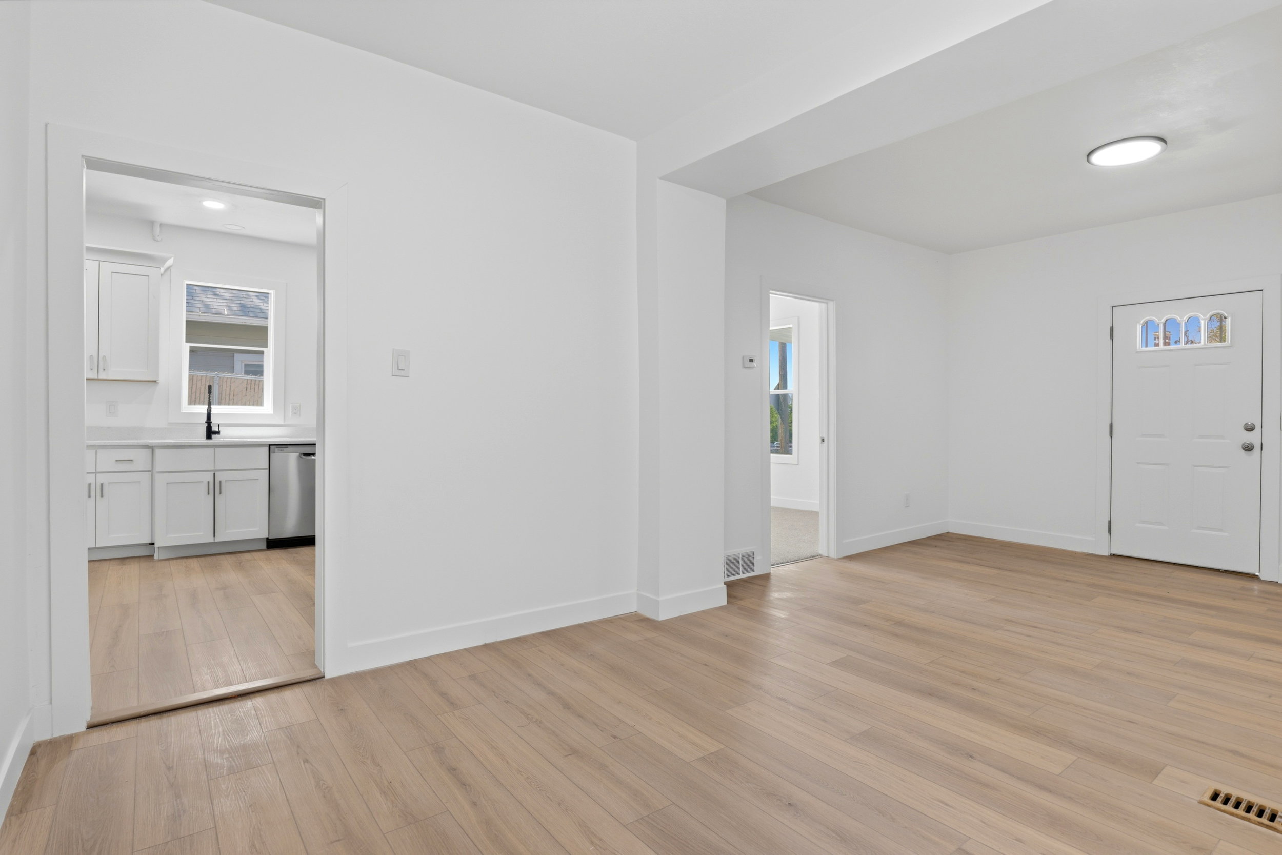 Open concept living space featuring light wood-finish flooring, white baseboards, and bright white walls