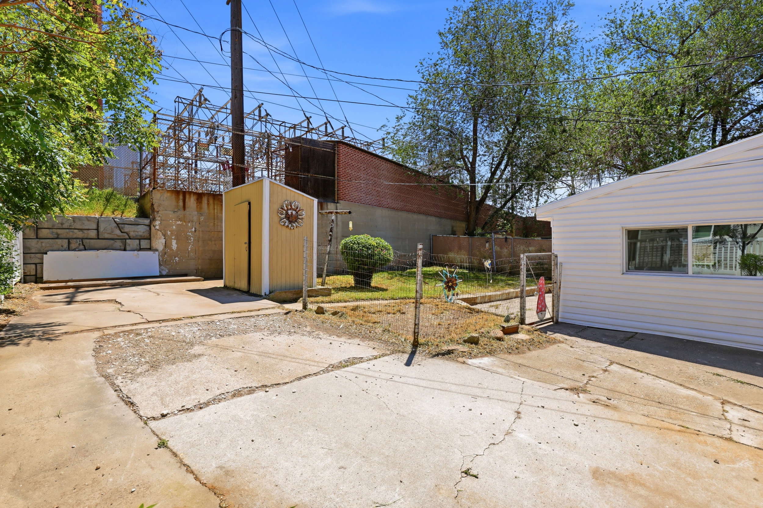 Concrete patio area with a detached storage shed and a retaining wall