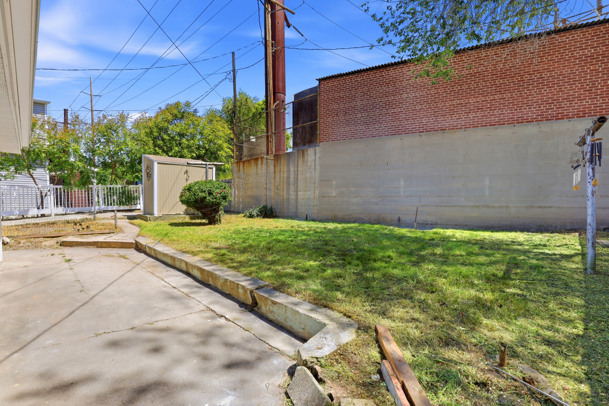 Expansive concrete patio with a retaining wall bordering a grassy yard