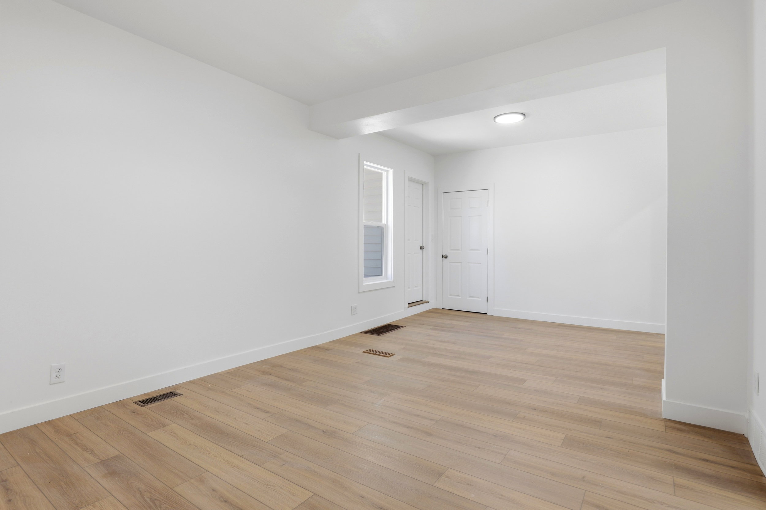 Spacious room featuring wood-finish flooring, white baseboards, and a neutral wall palette