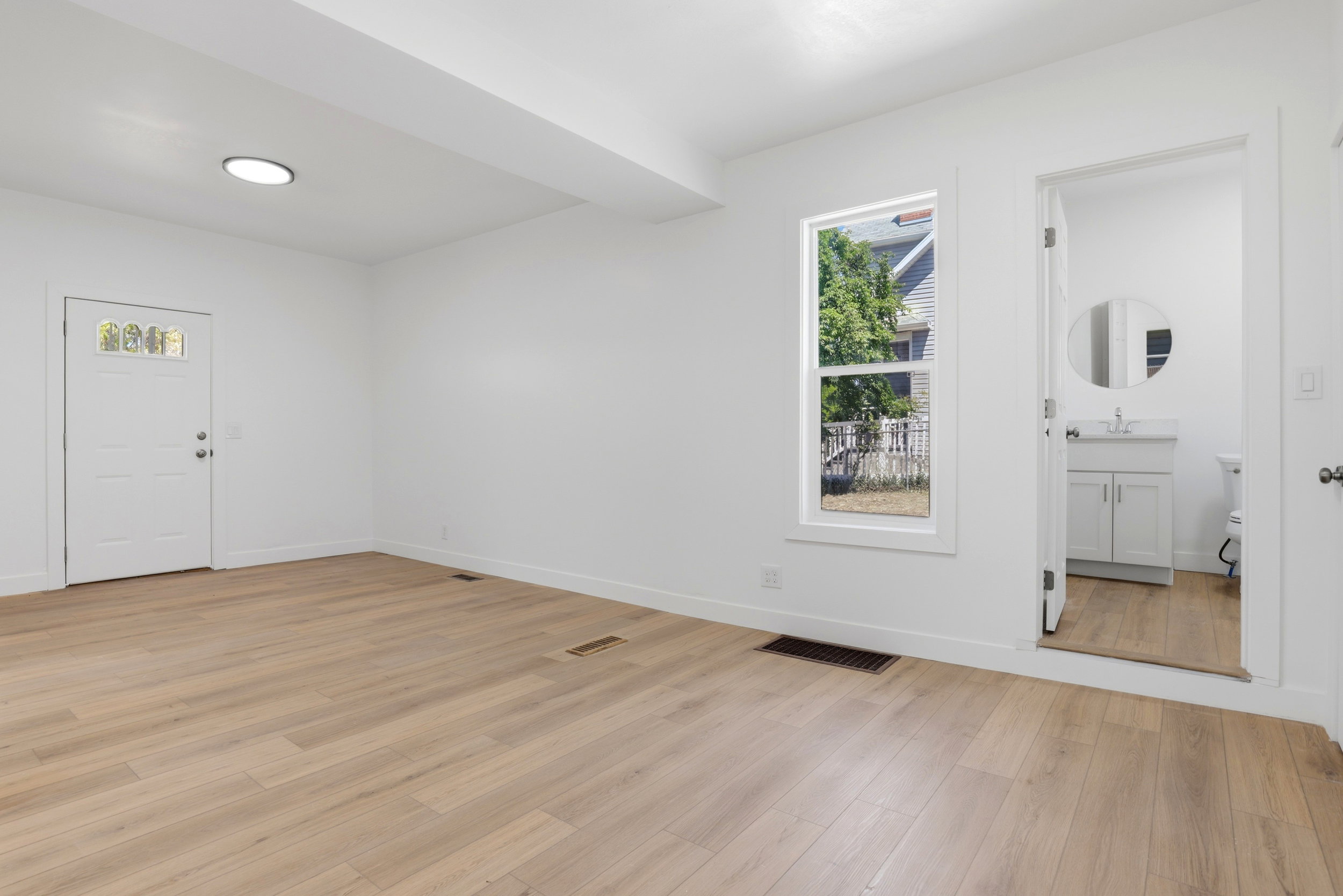Spacious room featuring light wood-finish flooring, white walls, and a recessed ceiling light