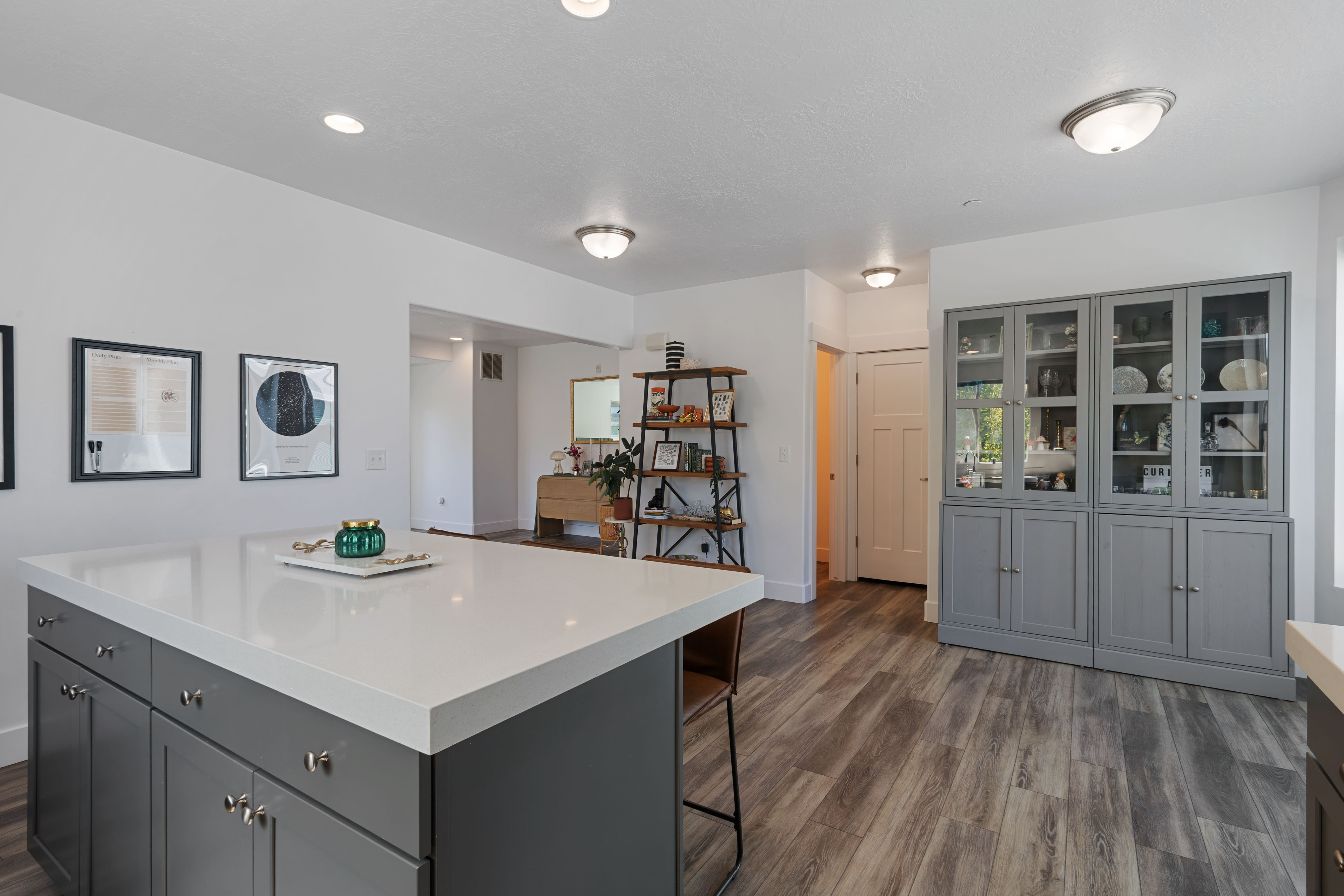 Spacious open-concept living area featuring an expansive kitchen island with a light-toned countertop, ample gray cabinetry, and recessed lighting