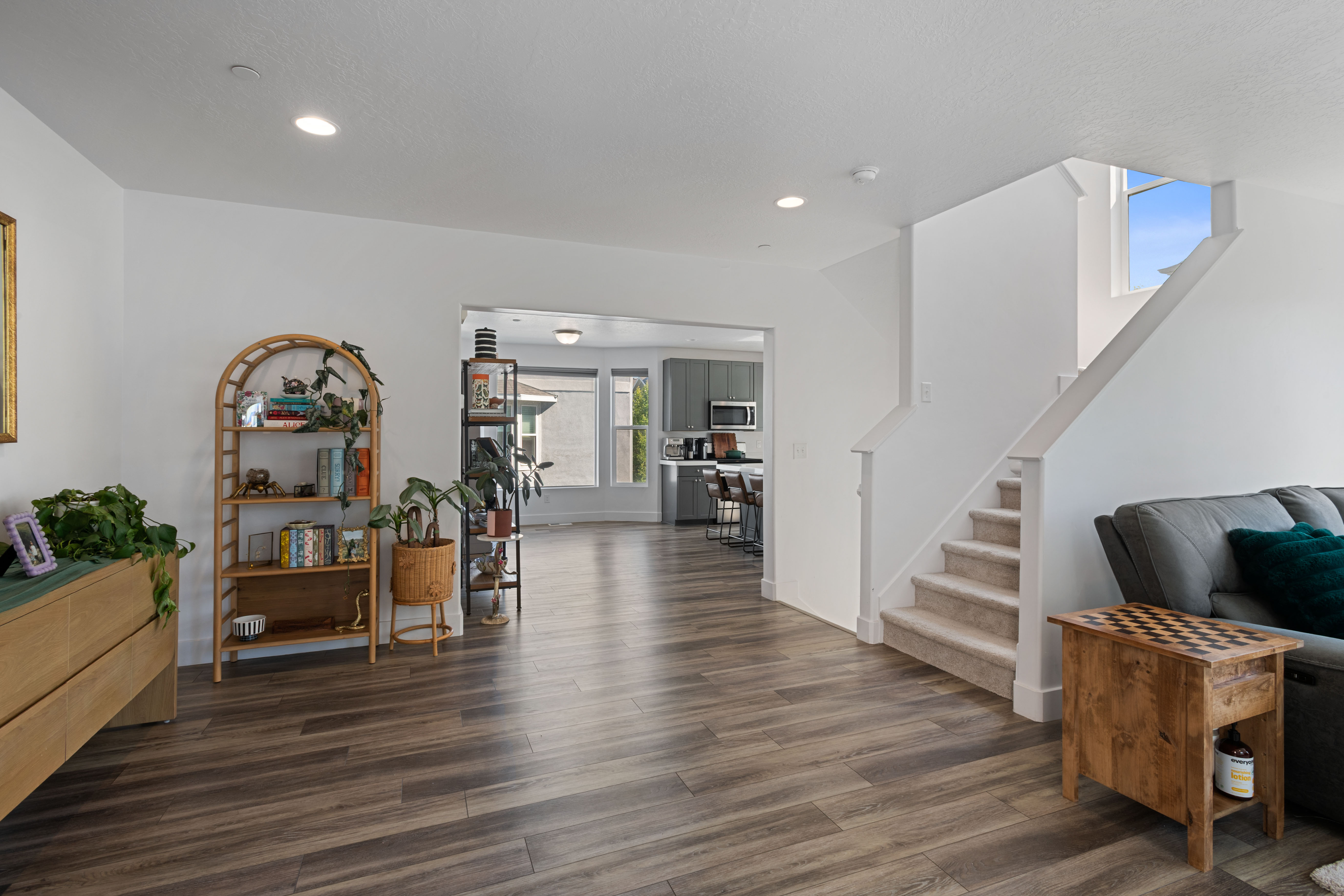 Open-concept interior featuring wood-finish flooring, recessed lighting, and a staircase with carpeted treads