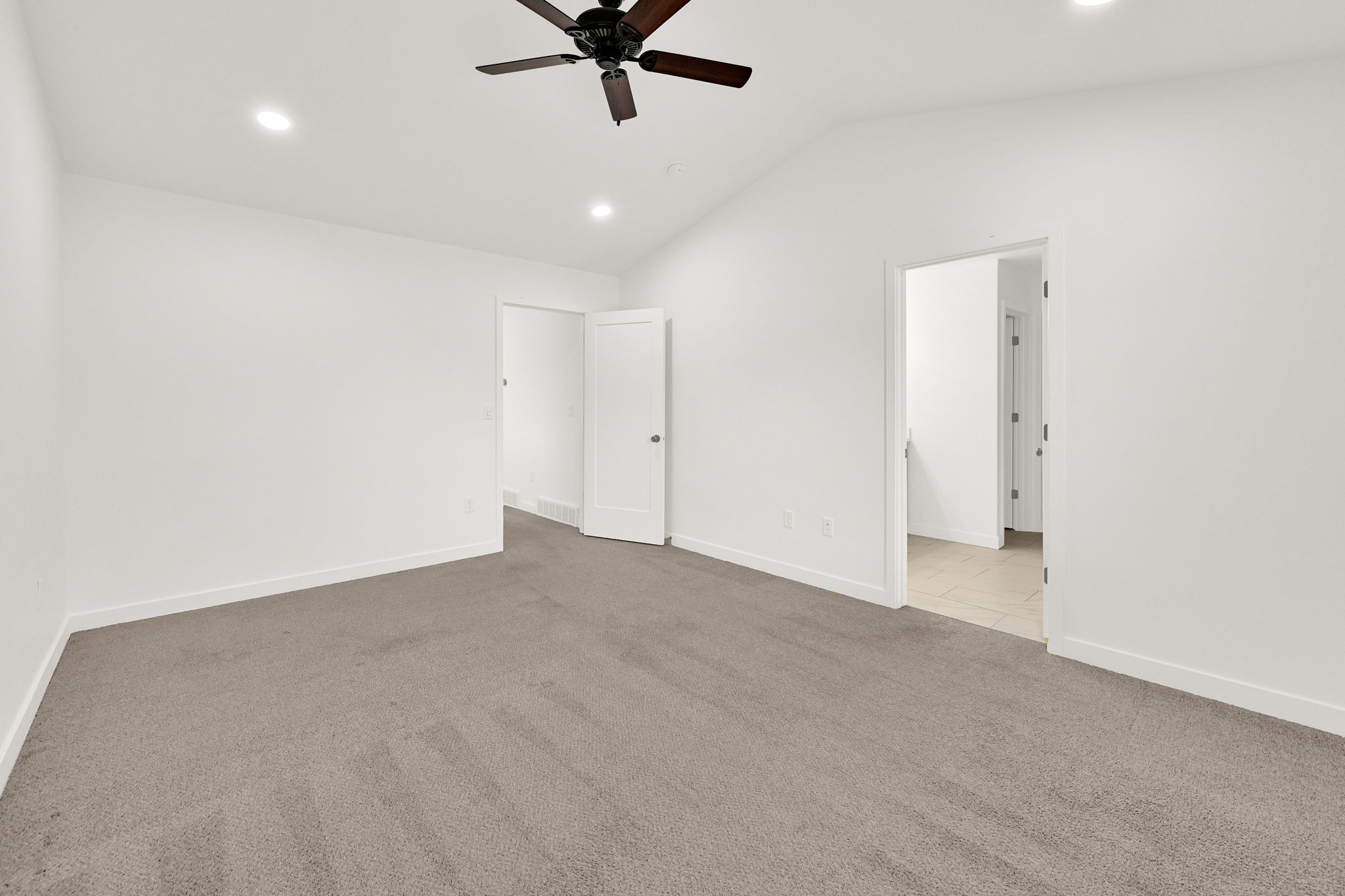 Spacious room featuring vaulted ceilings, recessed lighting, a ceiling fan, and plush carpet flooring