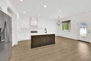 Kitchen featuring white cabinetry, subway tile backsplash, a dark wood-finish island with a white countertop, stainless steel appliances, and light wood-finish flooring