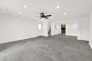 Spacious room featuring large format grey tile flooring, white walls, and recessed lighting