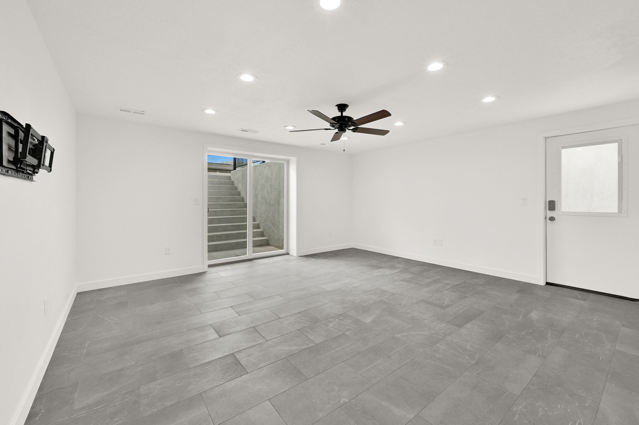 Spacious room featuring large format grey tile flooring, white walls, and recessed lighting