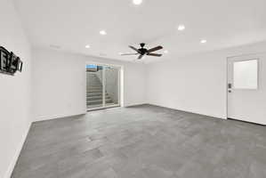 Spacious room featuring large format grey tile flooring, white walls, and recessed lighting