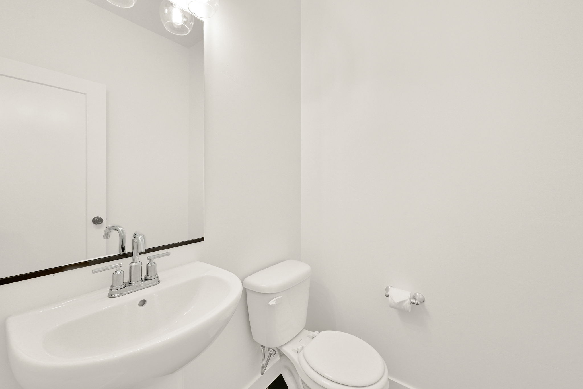 Pedestal sink with chrome faucet, mirror, and overhead vanity lighting