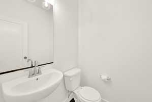 Pedestal sink with chrome faucet, mirror, and overhead vanity lighting