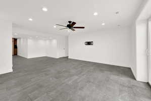 Spacious room featuring large format grey tile flooring, white walls, recessed lighting, and a ceiling fan
