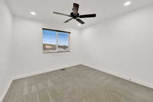 Carpeted interior space featuring a window with horizontal blinds, a dark-toned ceiling fan, and recessed ceiling lighting