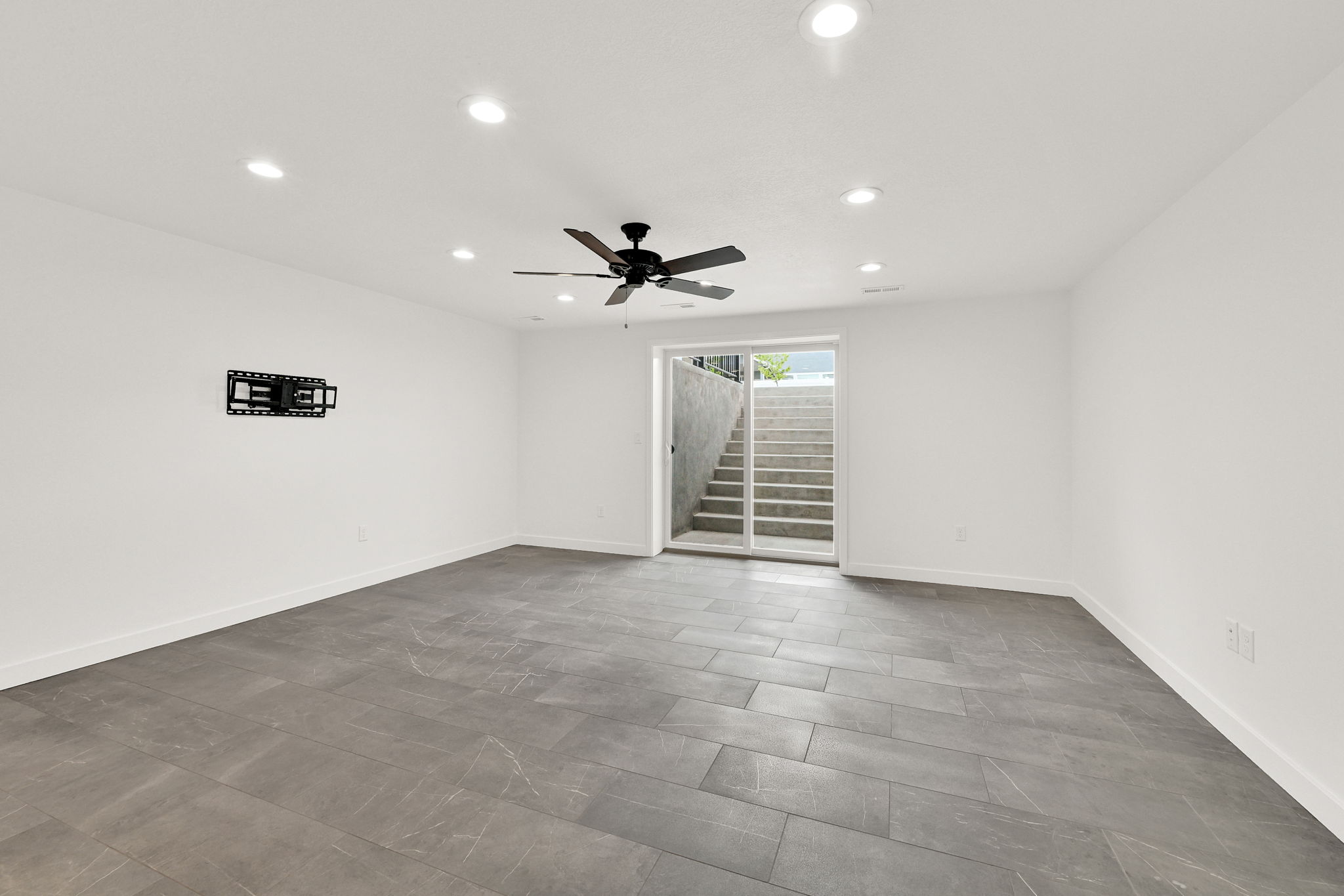 Spacious room featuring large format grey tile flooring, white walls, and recessed ceiling lighting