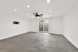 Spacious room featuring large format grey tile flooring, white walls, and recessed ceiling lighting