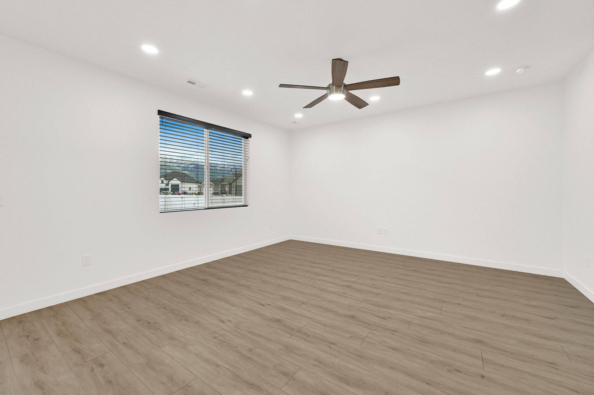 Spacious room featuring wood-finish flooring, recessed lighting, and a ceiling fan