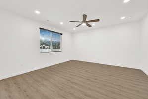 Spacious room featuring wood-finish flooring, recessed lighting, and a ceiling fan