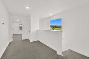 Upper-level hallway with neutral carpeting, recessed lighting, white trim, and a window offering a mountain and landscape backdrop