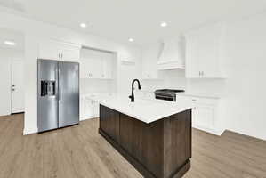 Kitchen featuring a dark wood-finish island with a white countertop, contrasting with white perimeter cabinetry and subway tile backsplash