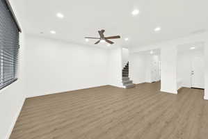 Spacious main living area featuring wood-finish flooring, a ceiling fan with integrated lighting, recessed overhead lighting, and window blinds