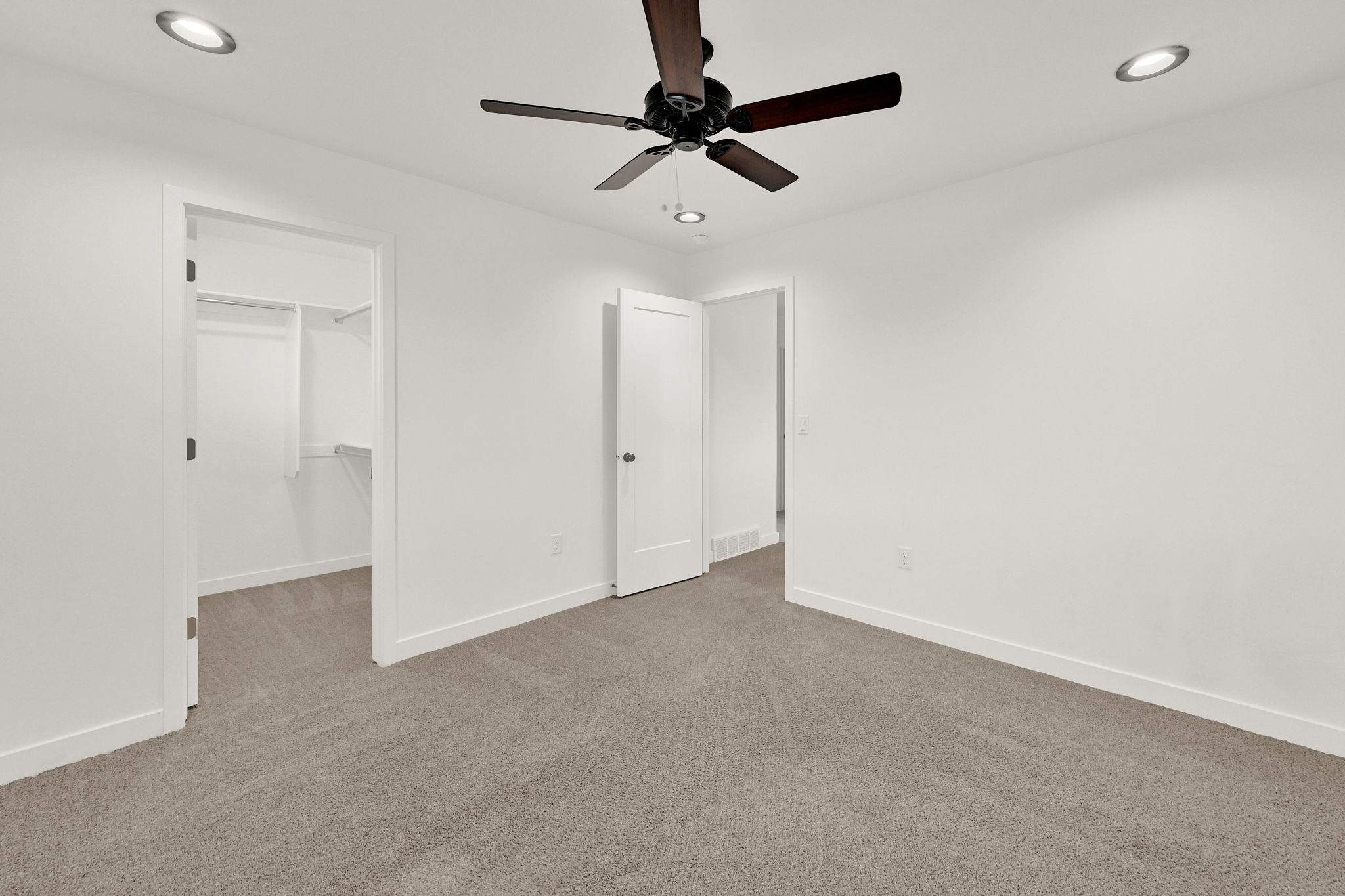 Neutral tone walls with recessed lighting and a ceiling fan