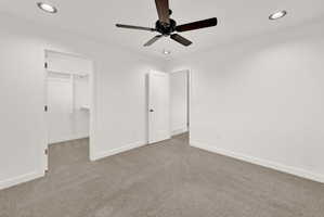 Neutral tone walls with recessed lighting and a ceiling fan