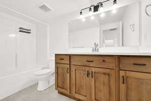Bathroom featuring a wide wood-finish vanity with a light-colored countertop, large wall-mounted mirror, and a 4-light fixture with clear glass globes
