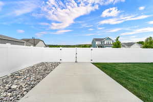 Expansive fenced backyard featuring a concrete patio, a gravel border, and a manicured lawn