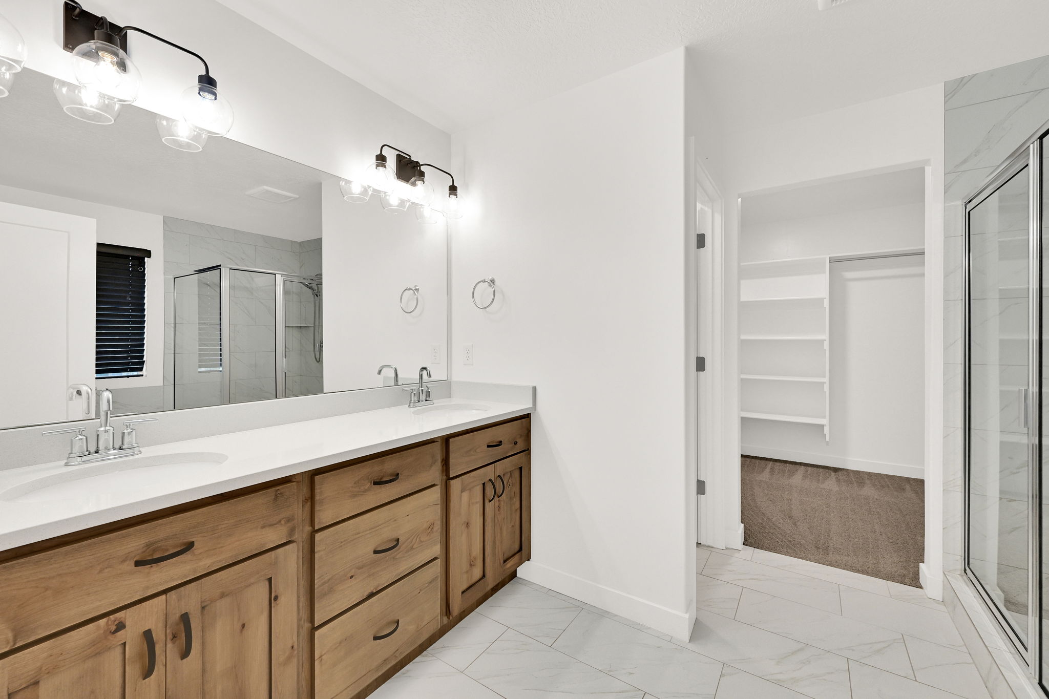 Bathroom featuring a dual vanity with light-tone wood cabinetry, white countertops, and a large mirror