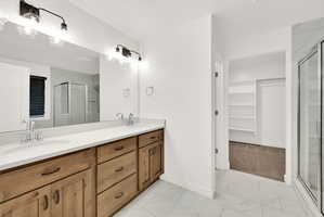 Bathroom featuring a dual vanity with light-tone wood cabinetry, white countertops, and a large mirror