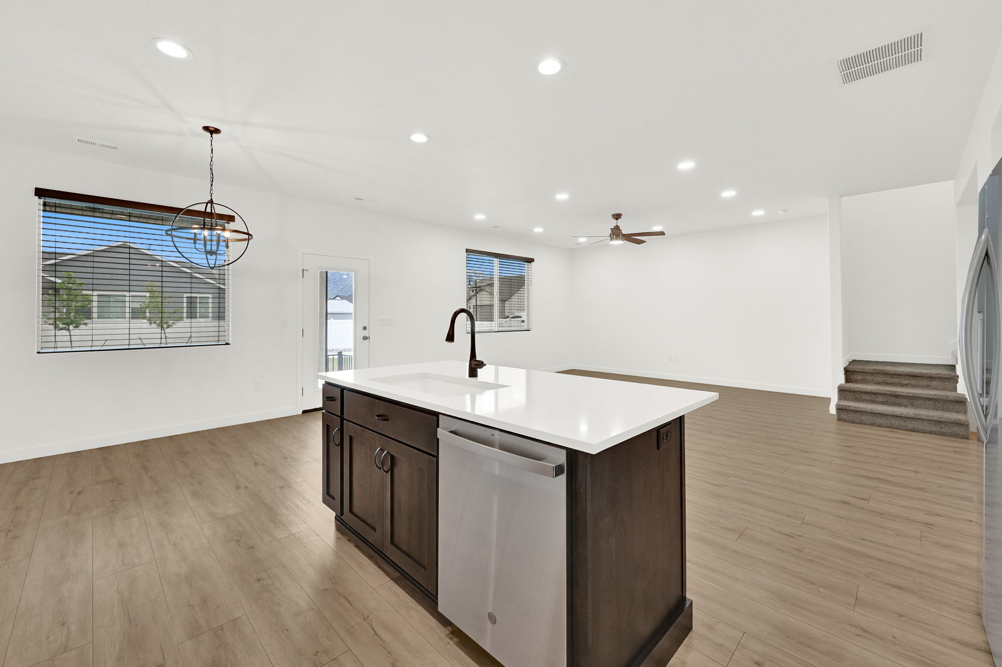 Kitchen island with a white countertop, integrated sink, matte black faucet, and stainless steel dishwasher