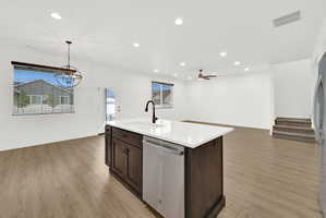 Kitchen island with a white countertop, integrated sink, matte black faucet, and stainless steel dishwasher