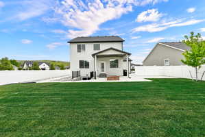 Expansive rear yard featuring a large grass lawn, a white privacy fence, and a concrete patio
