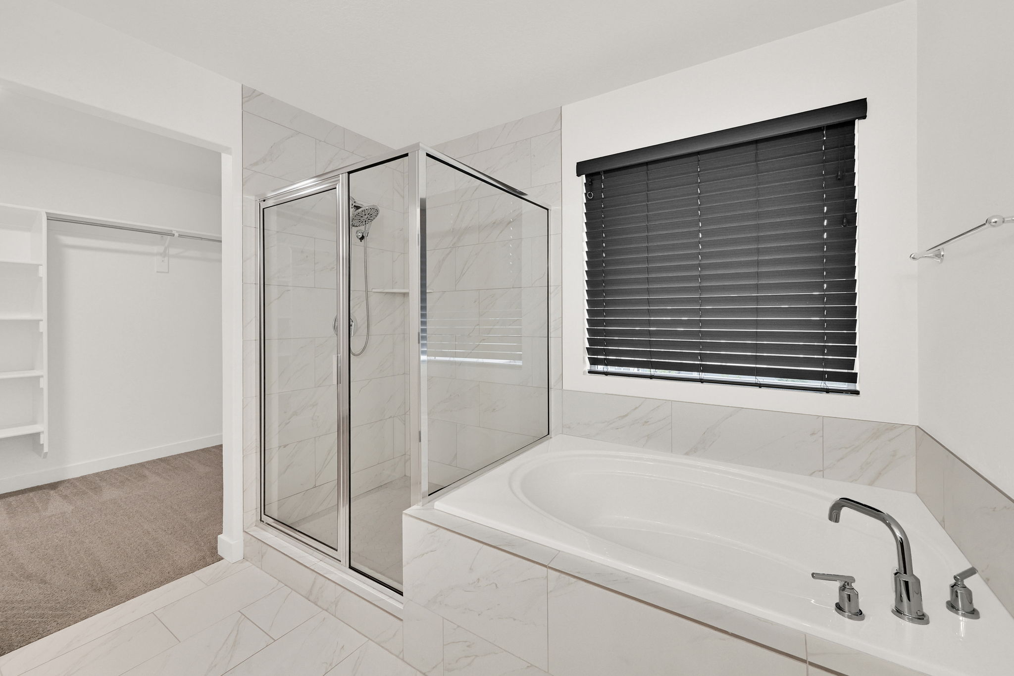 Spacious bathroom featuring a built-in soaking tub, a separate glass-enclosed shower, polished chrome fixtures, and marble-look tile flooring and surrounds