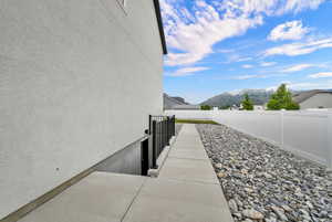 Stucco exterior with a concrete walkway, rock landscaping, and a white privacy fence