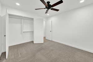Spacious room featuring neutral carpeting, recessed lighting, and a ceiling fan with dark wood-finish blades