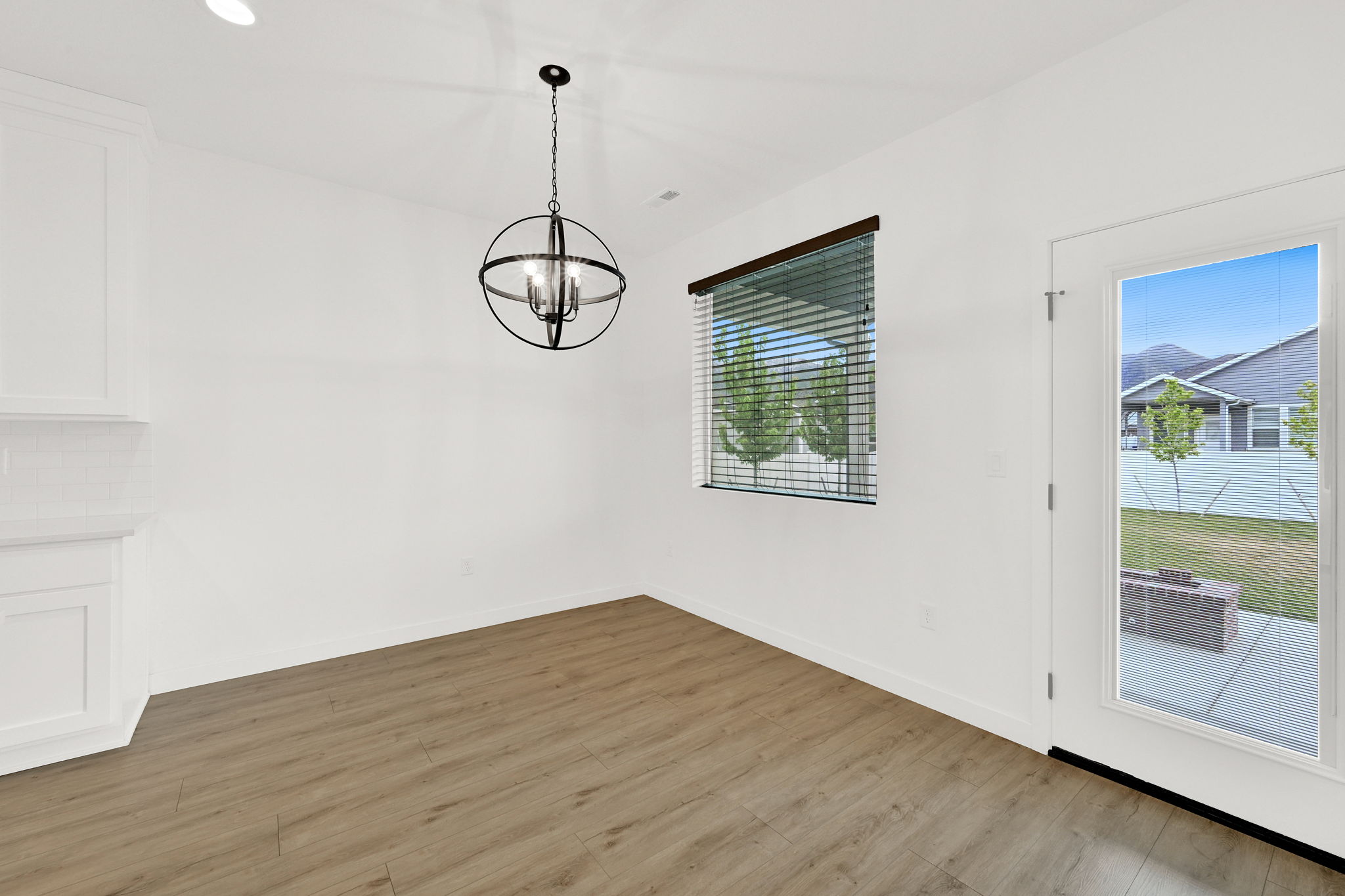 Bright dining space featuring wood-finish flooring, a contemporary globe chandelier, and built-in white cabinetry