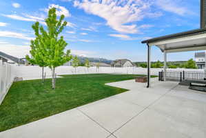 Expansive backyard featuring a manicured lawn, established trees, and a white privacy fence