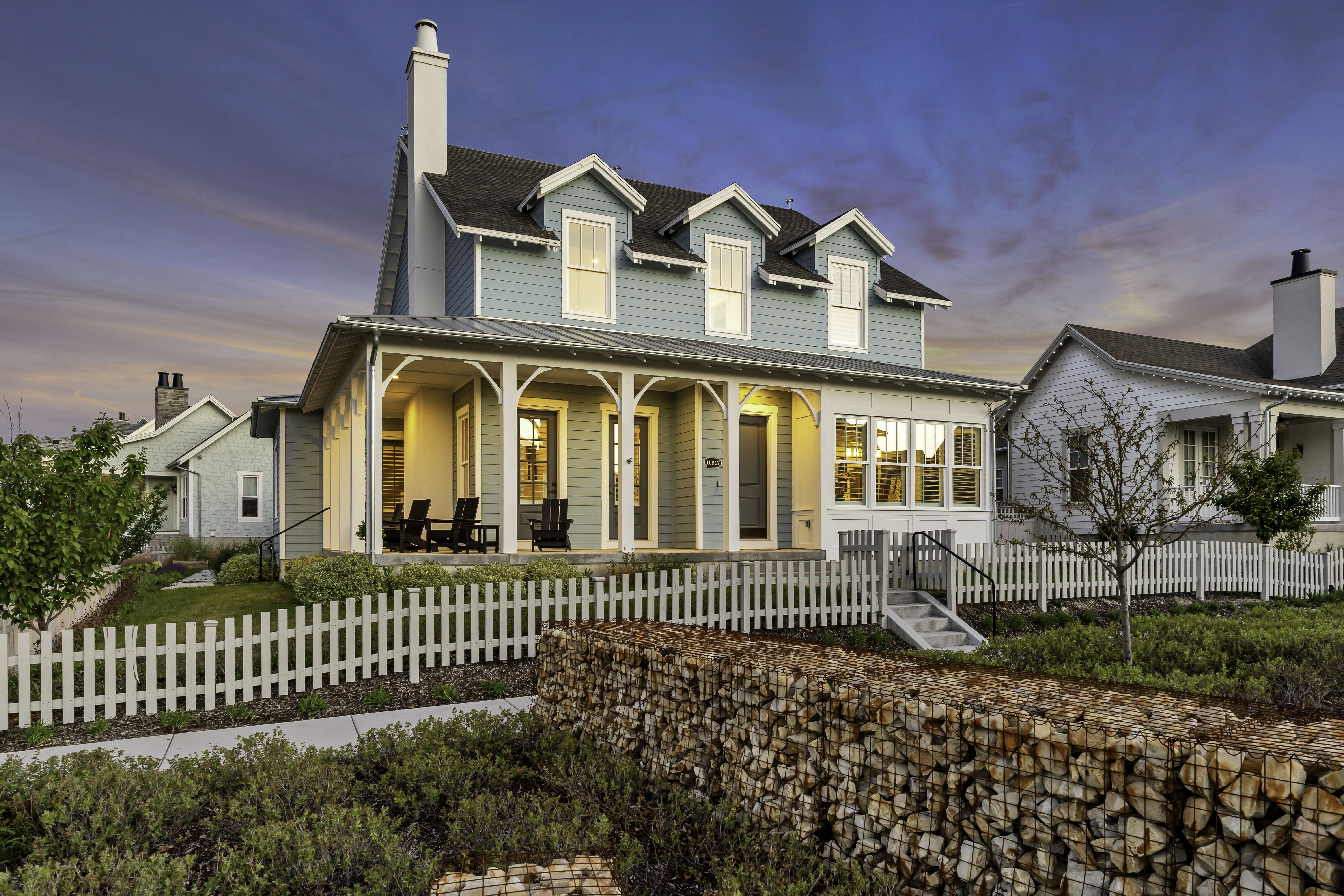 Two-story residence featuring light blue siding, dormer windows, and a white picket fence