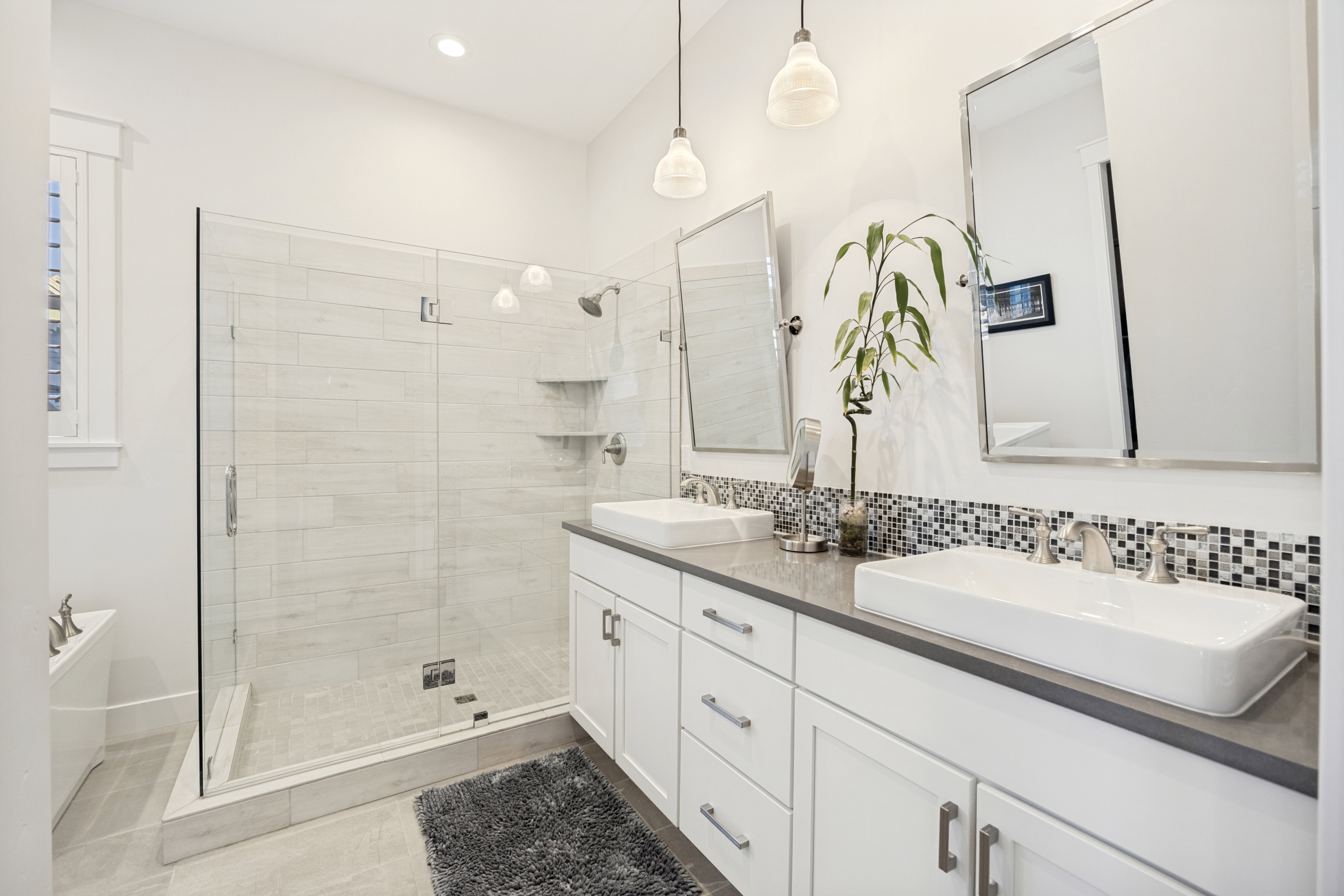 Modern bathroom featuring a dual vanity with rectangular vessel sinks, quartz countertops, and white shaker-style cabinetry