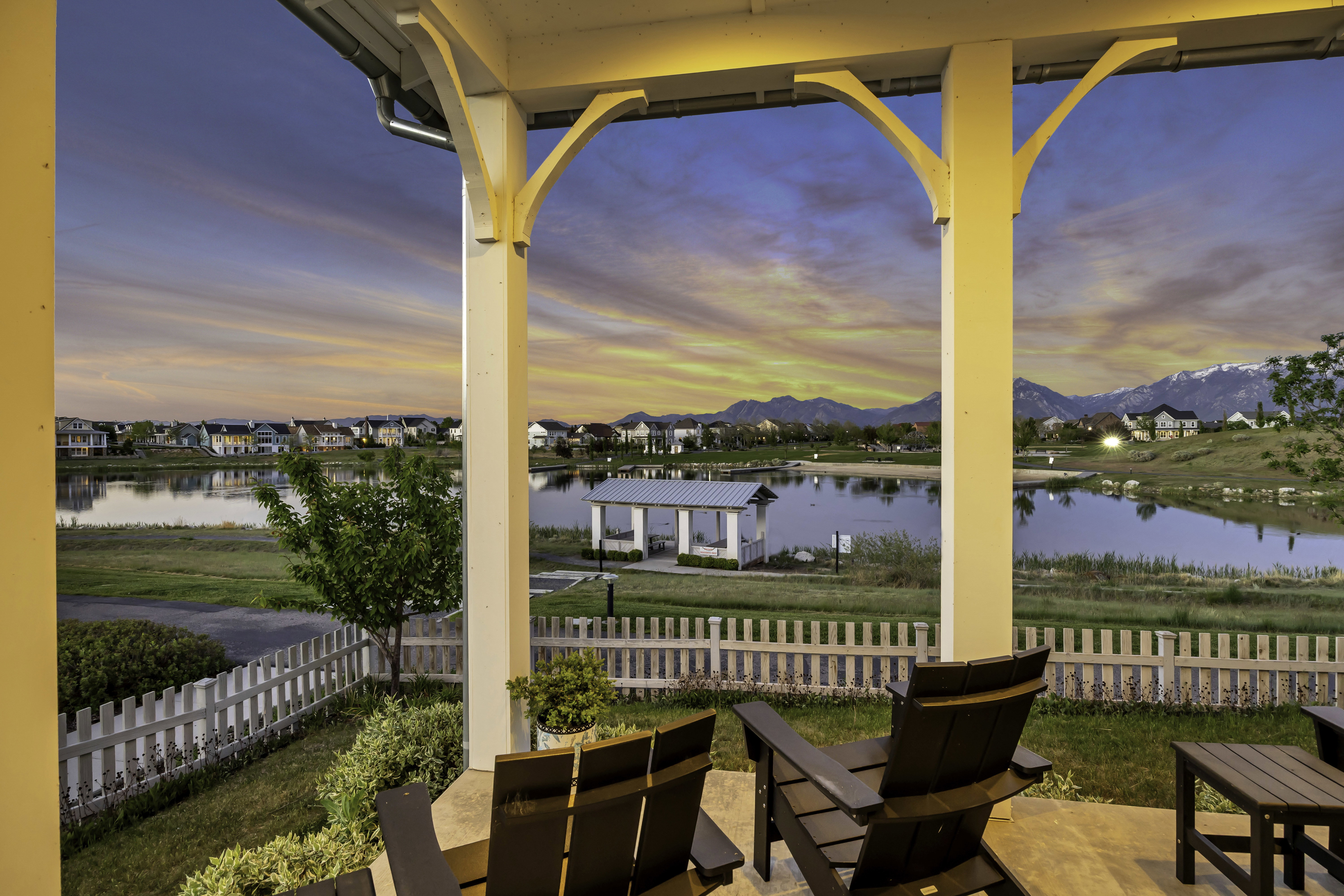 Covered patio featuring architectural columns and corbels, offering a lakefront setting and mountain backdrop