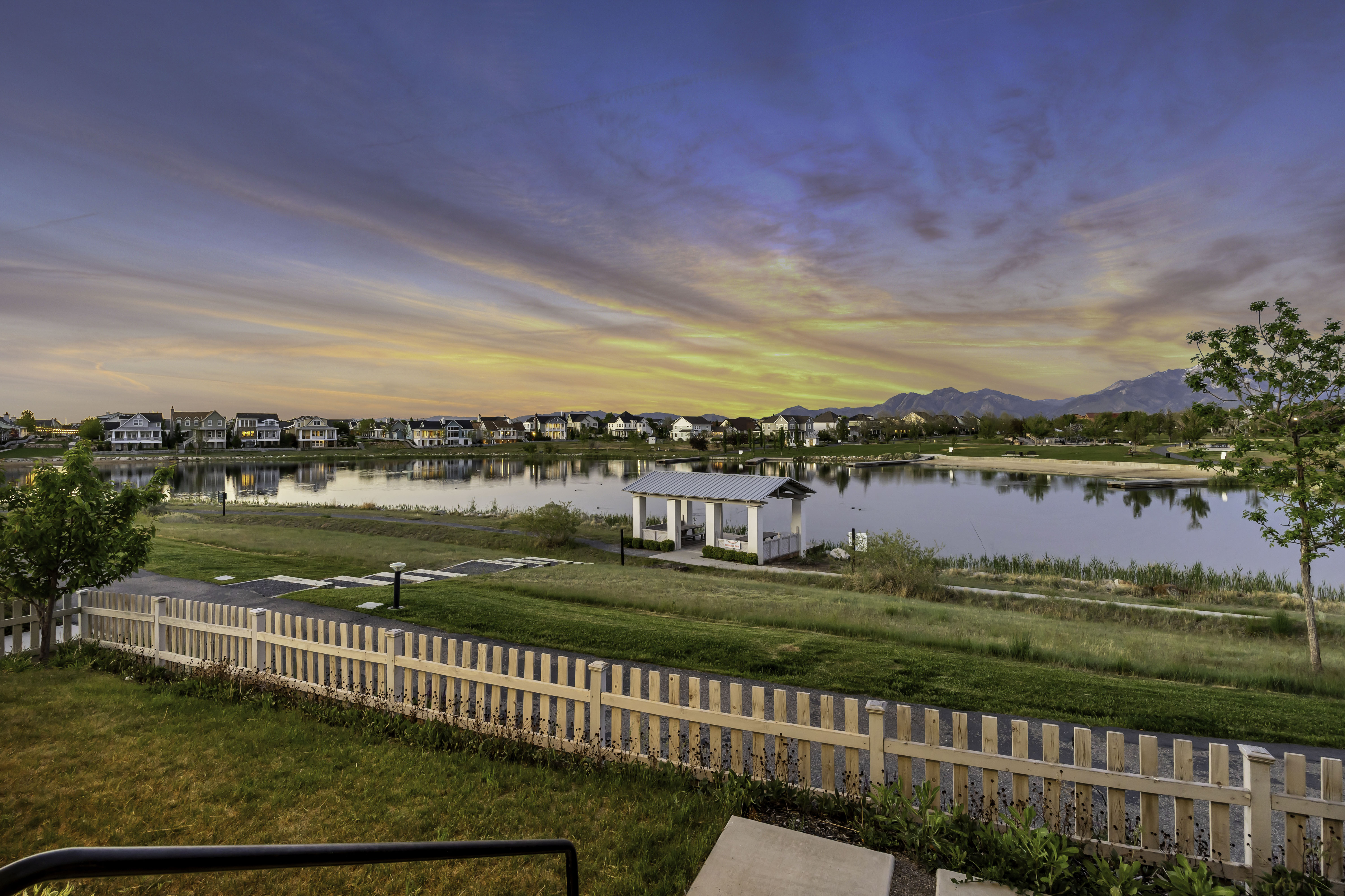 Expansive waterfront scenery featuring a tranquil lake, distant mountains, and a charming lakeside gazebo