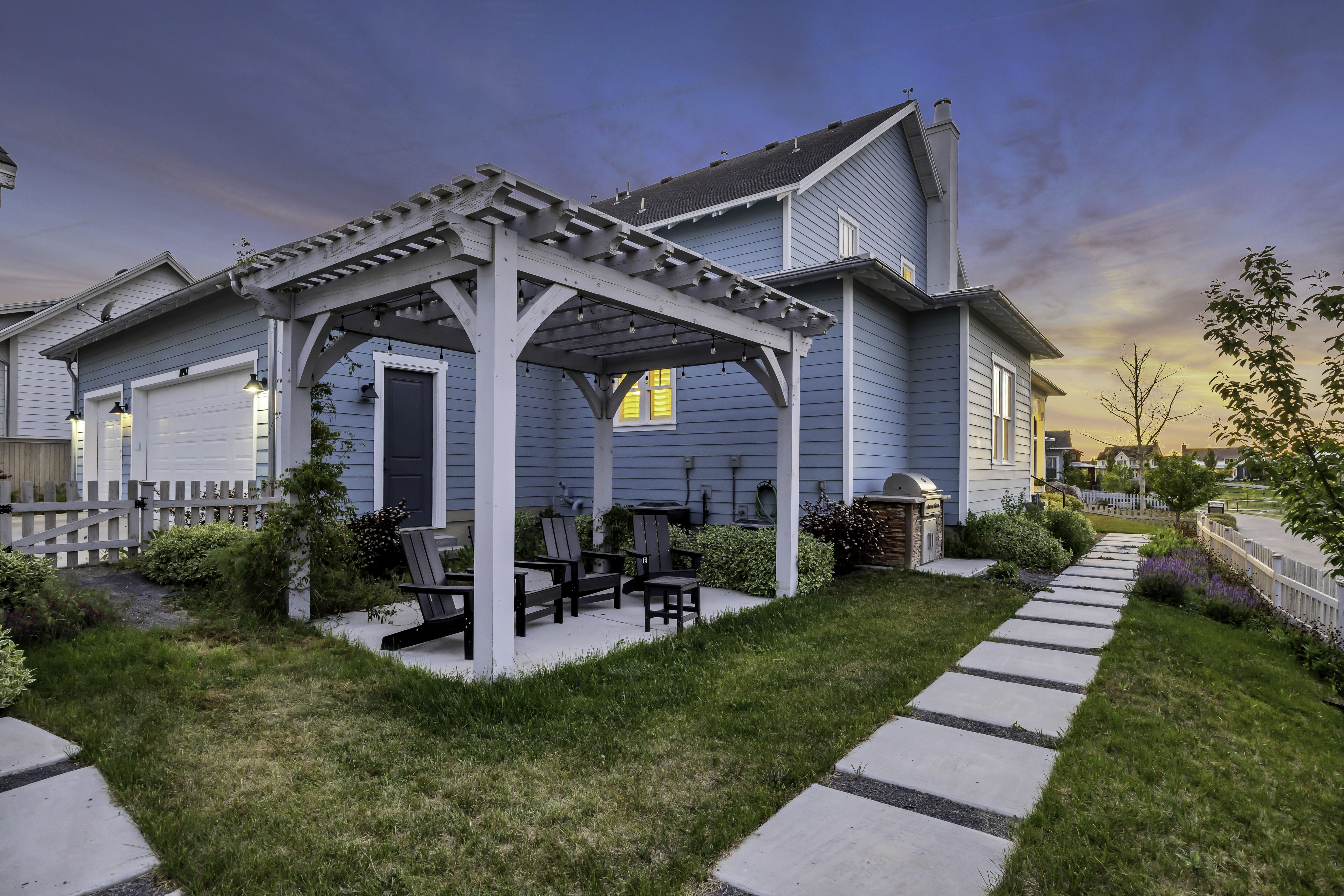 Exterior featuring a light blue siding, a white pergola with string lights, and a concrete patio with seating