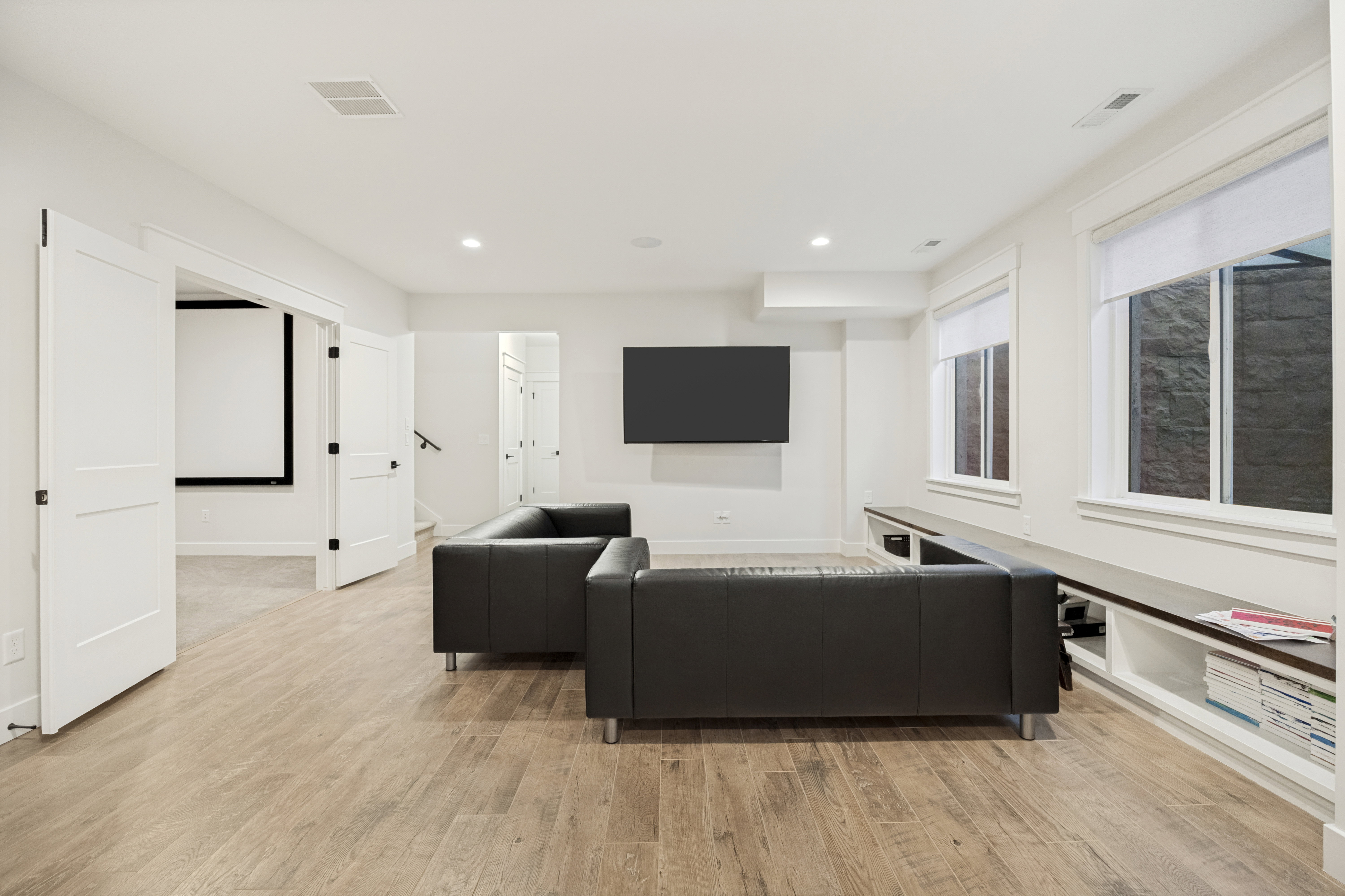 Spacious living area featuring light wood-finish flooring and recessed lighting