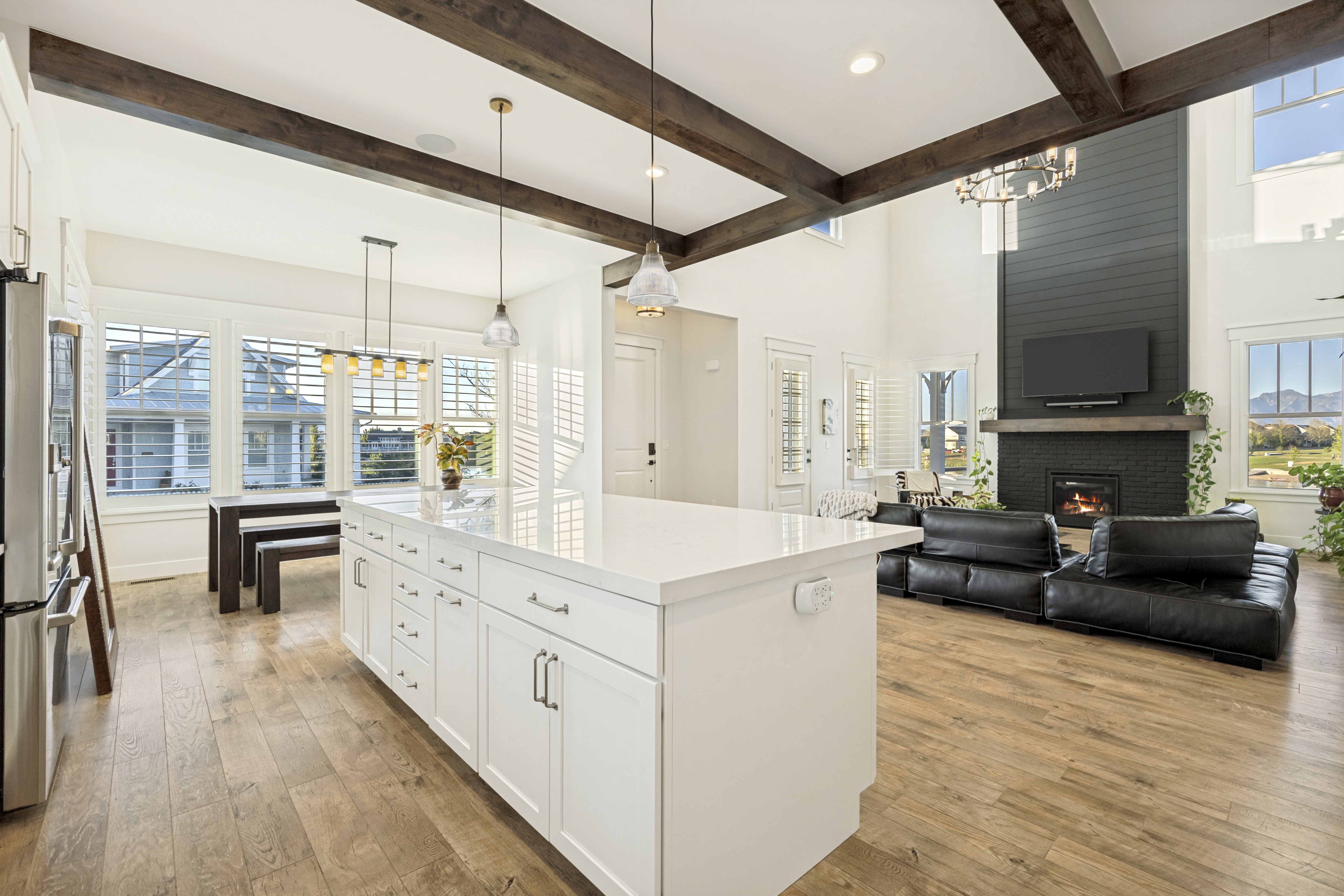 Open-concept living area featuring exposed wood beams, wood-finish flooring, and a soaring vaulted ceiling