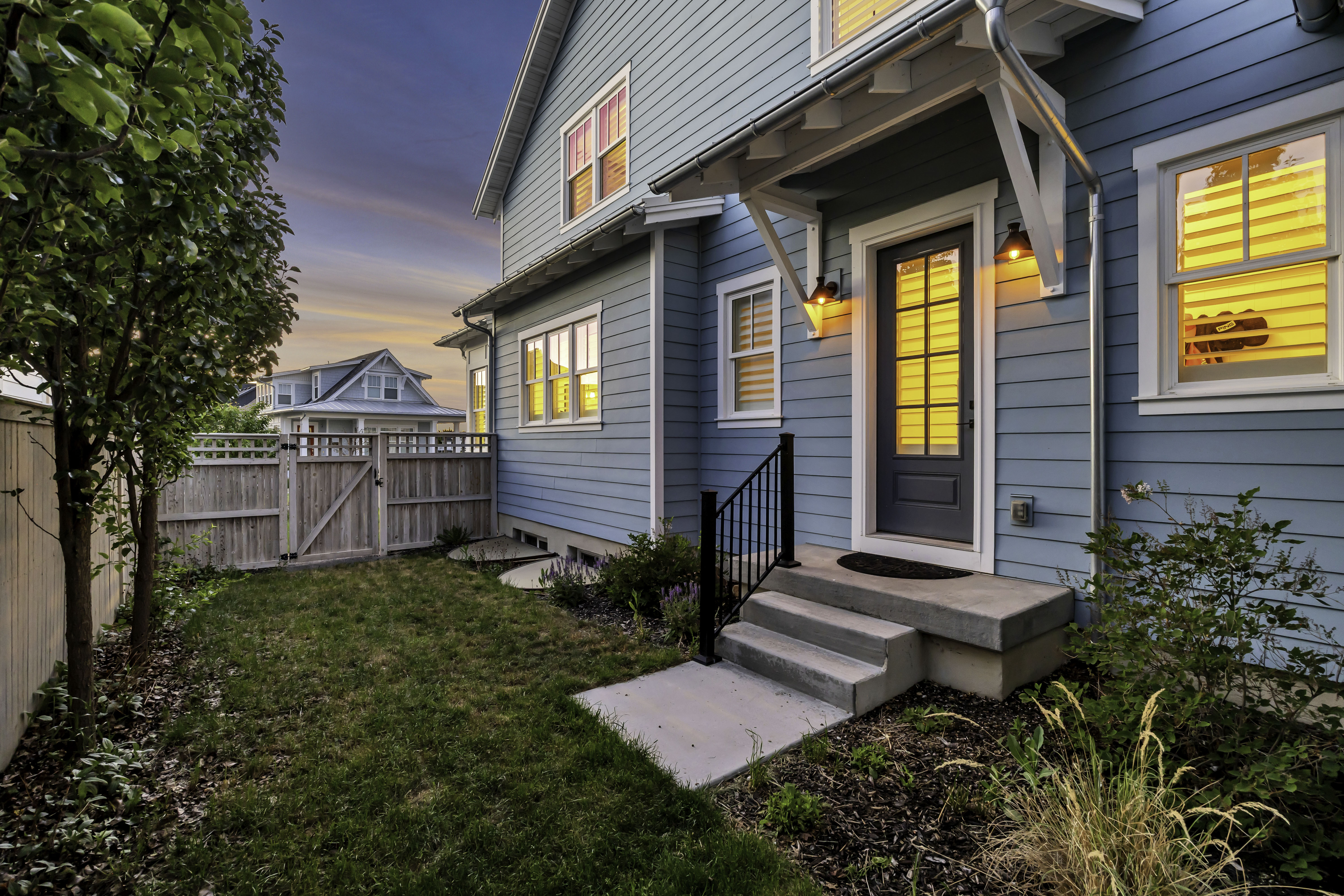 Light blue horizontal siding exterior with white trim, featuring a dark gray front door with glass panels and a white overhang