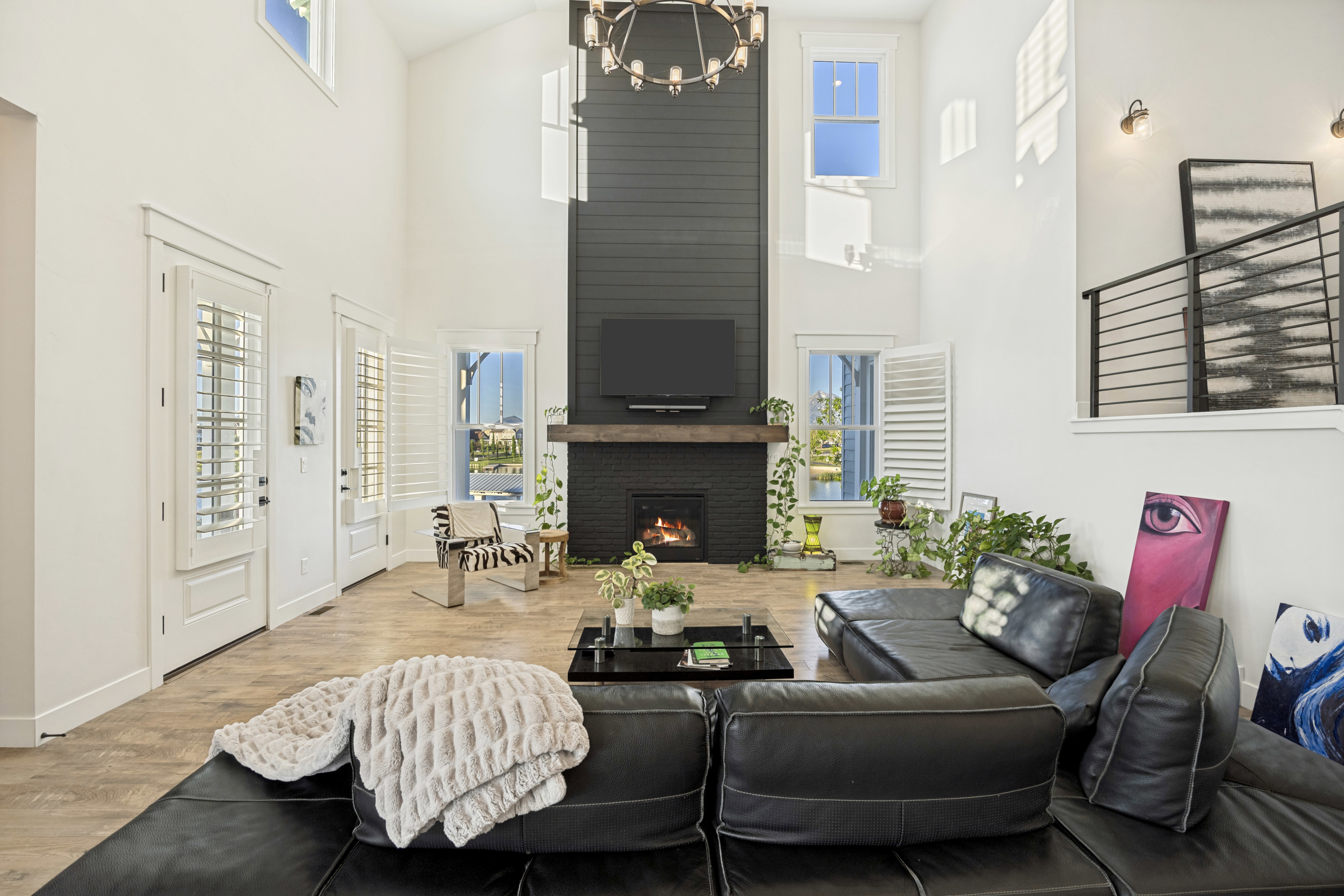Great room featuring vaulted ceilings, a two-story shiplap fireplace surround, a wood-finish mantel, and a black brick firebox
