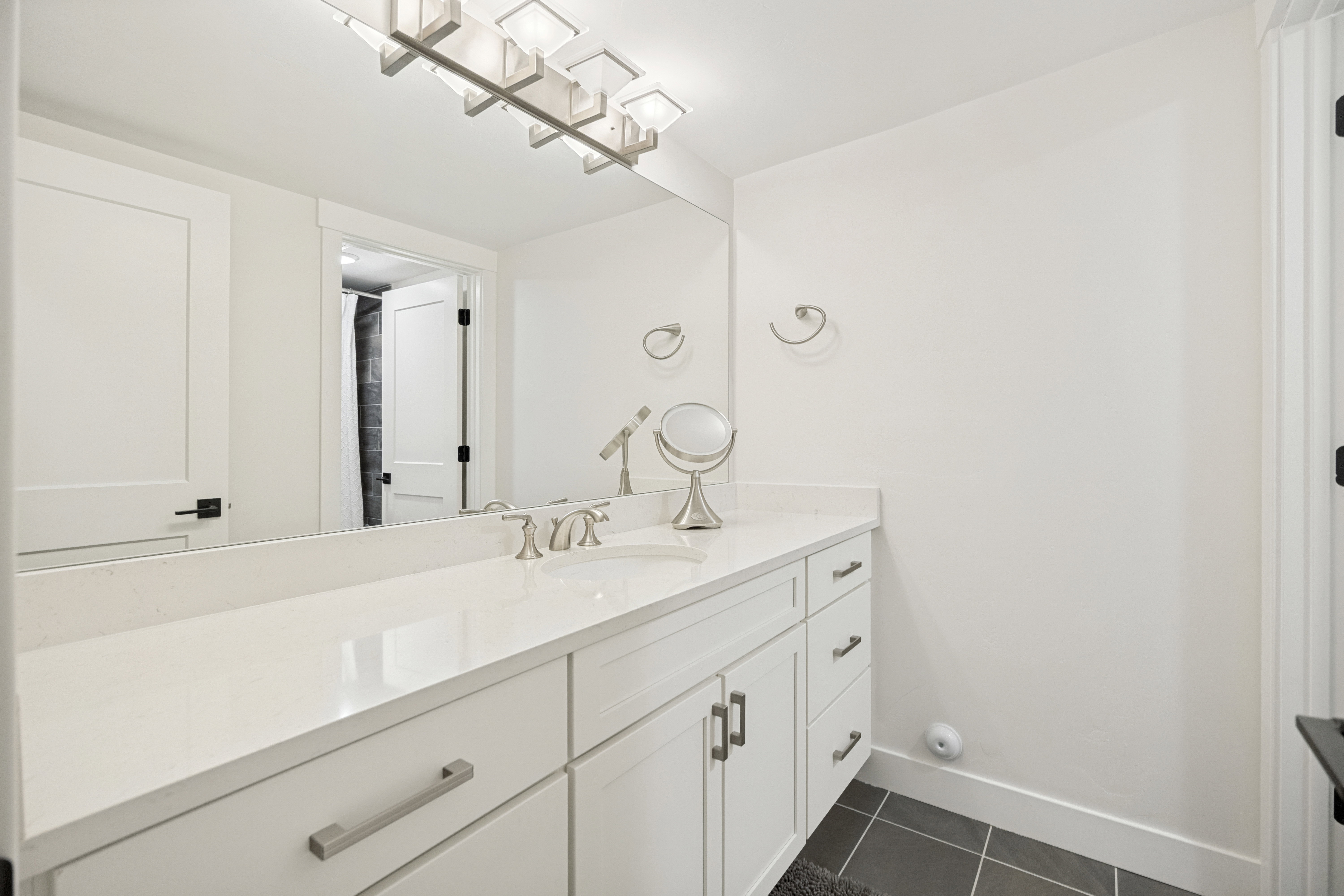 Vanity featuring a white countertop with an integrated sink, brushed nickel faucet, and a large mirror