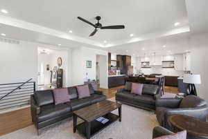 Open-concept living area featuring light wood-finish flooring, a contemporary ceiling fan, recessed lighting, and a white interior paint scheme