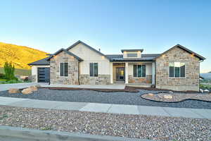 Modern ranch-style home featuring a stone and board-and-batten facade, a dark gray roof, and a contemporary garage door